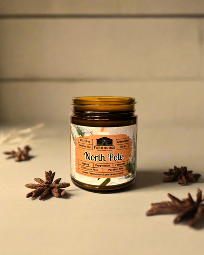 North Pole Soy Candle by Farmhouse Charm Candles, an 8 oz natural soy wax candle featuring a blend of buttery eggnog, peppermint, cinnamon, and pinecone scents, with a crackling wooden wick for up to 50 hours of burn time, presented in an eco-friendly amber jar.