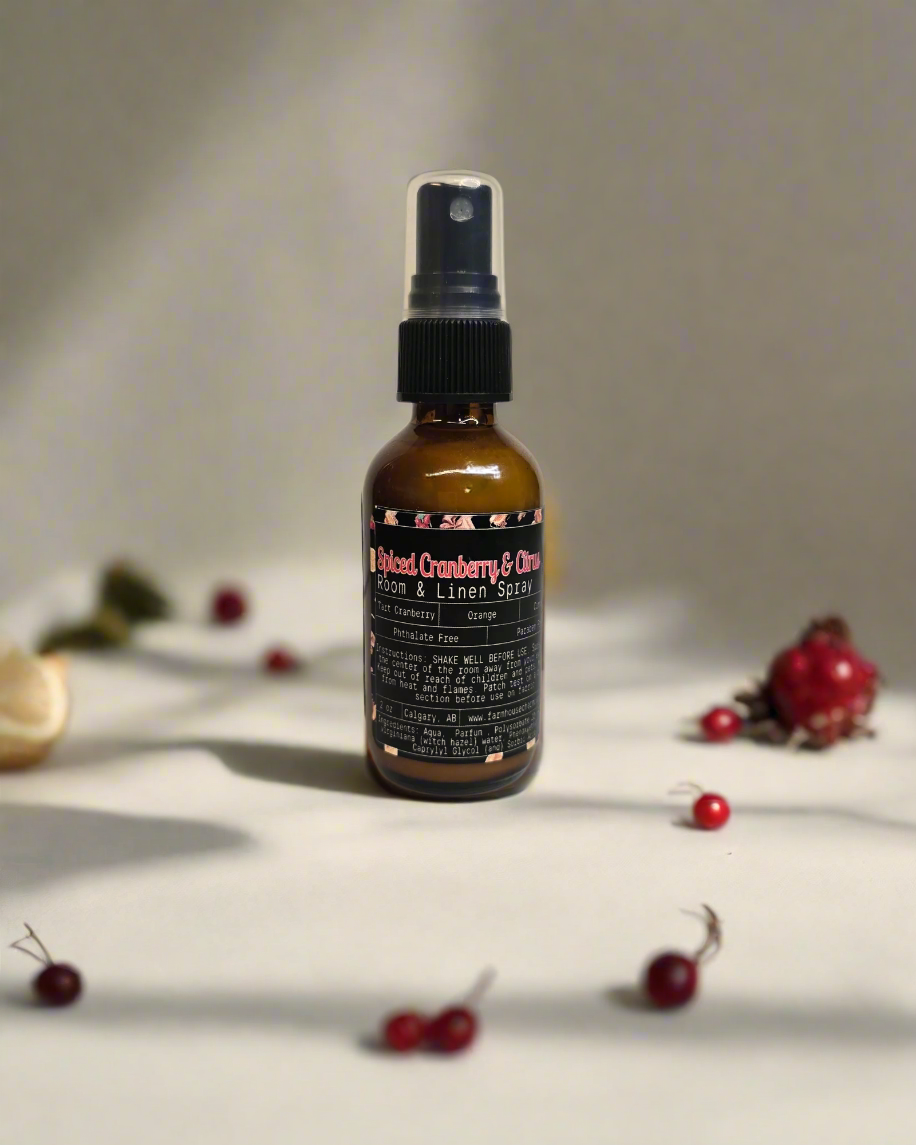 Spiced Cranberry Room and Linen Spray bottle displayed with festive background, featuring seasonal scents of tart cranberry, mulberry, tangy orange, spicy clove, and warm cinnamon. Perfect for adding a cozy and refreshing holiday aroma to any room or fabric.